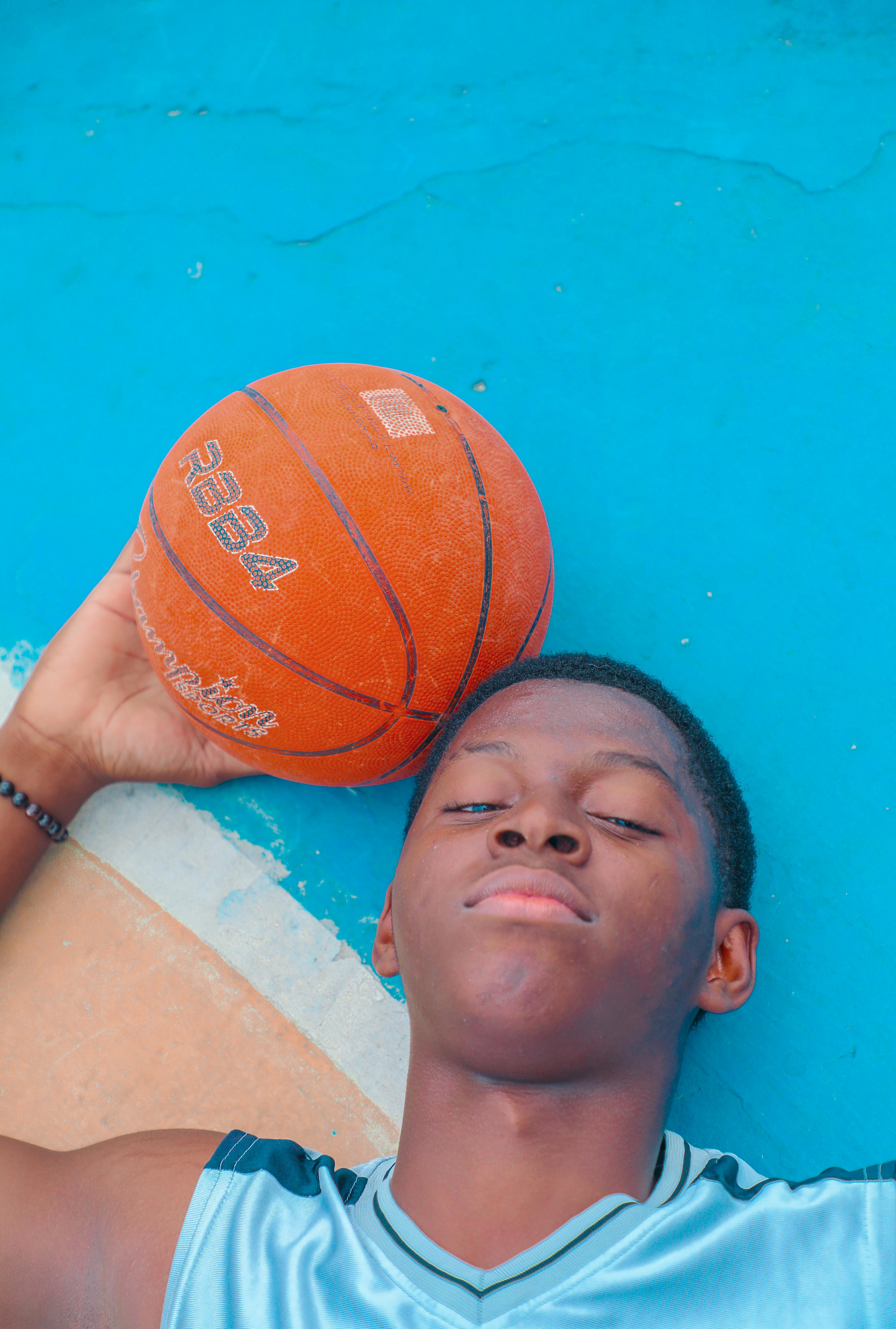 a young man laying on a basketball court with his head on the ball