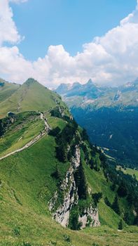 Breathtaking view of lush green mountains and valleys under a clear blue sky in summer.