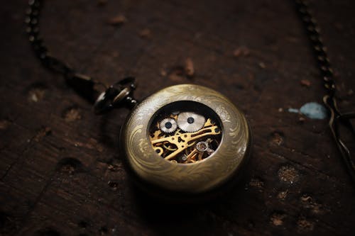 Free Silver-colored Pocket Watch on Brown Wooden Surface Stock Photo