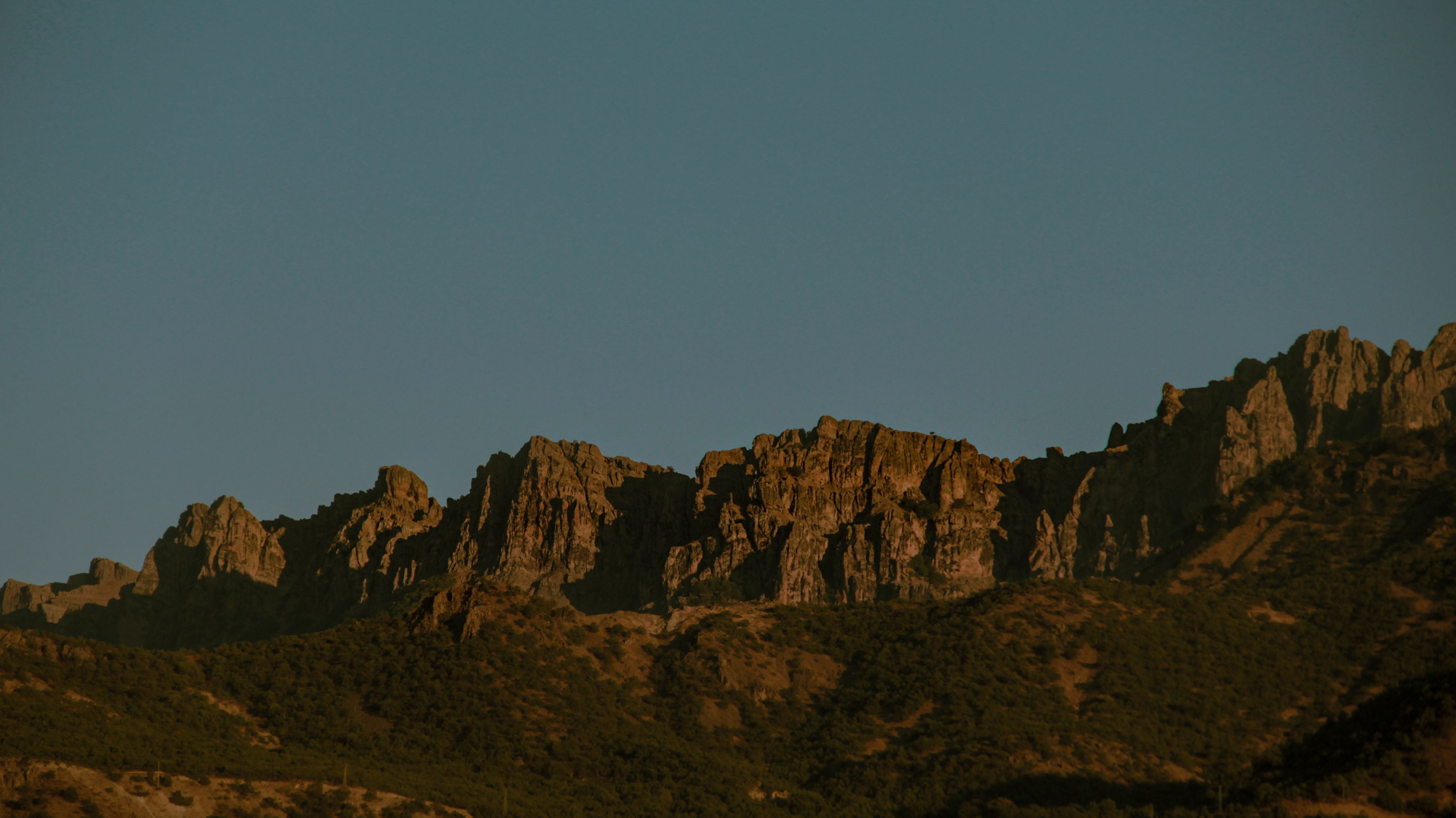 A mountain range with a blue sky in the background · Free Stock Photo