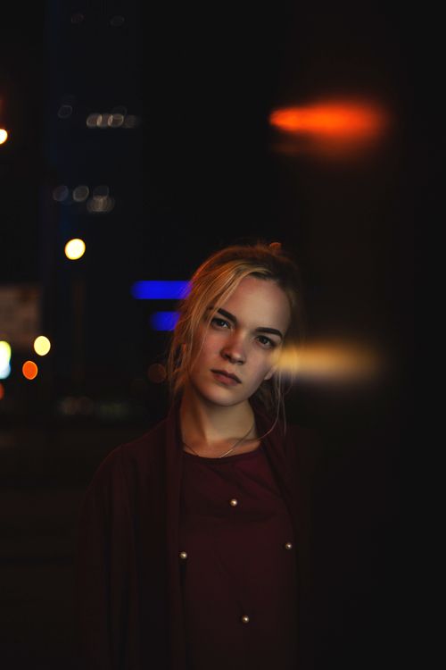 Free A captivating portrait of a young woman with a dreamy expression under city lights. Stock Photo