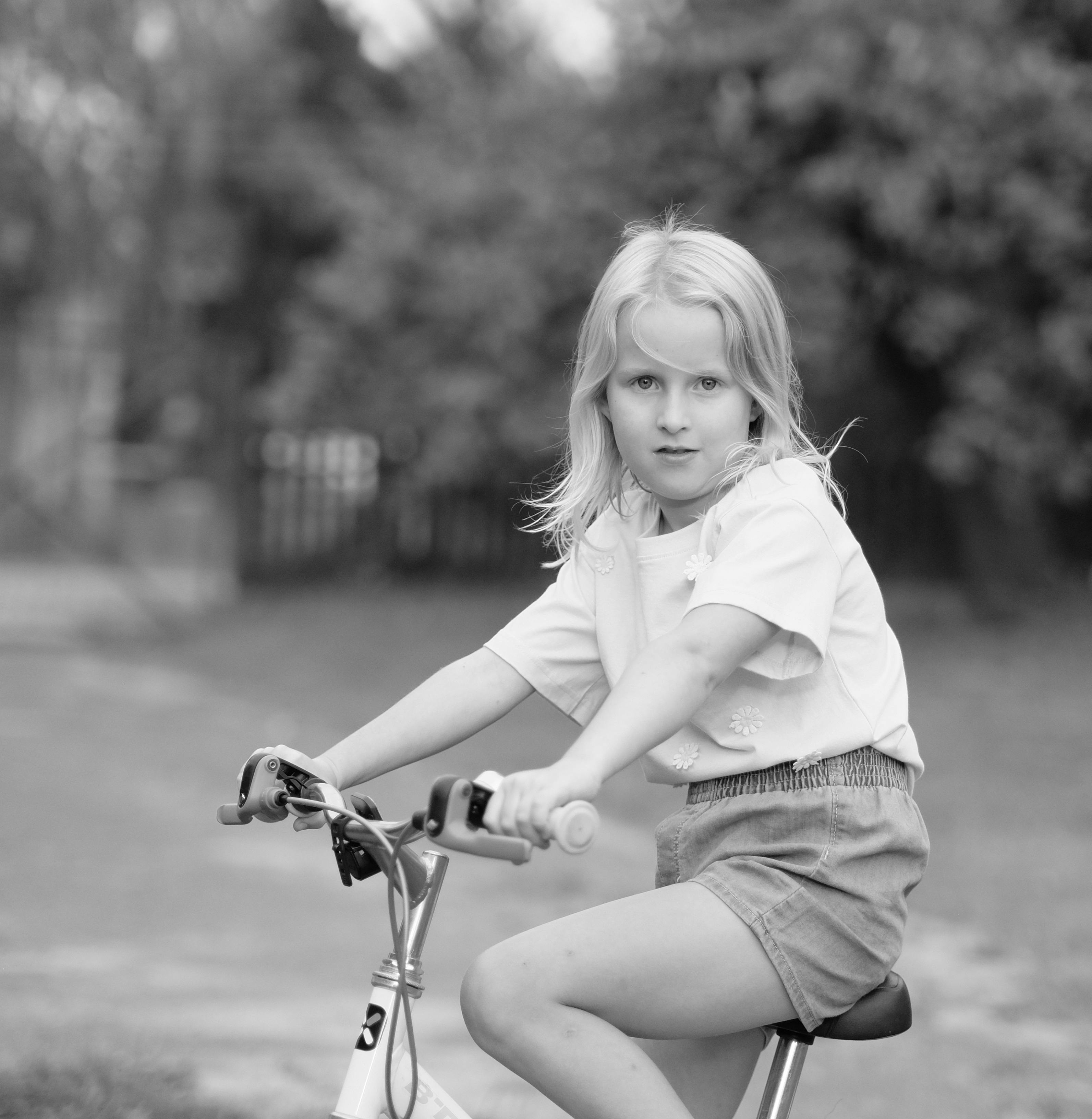 a black and white photo of a little girl riding a bike