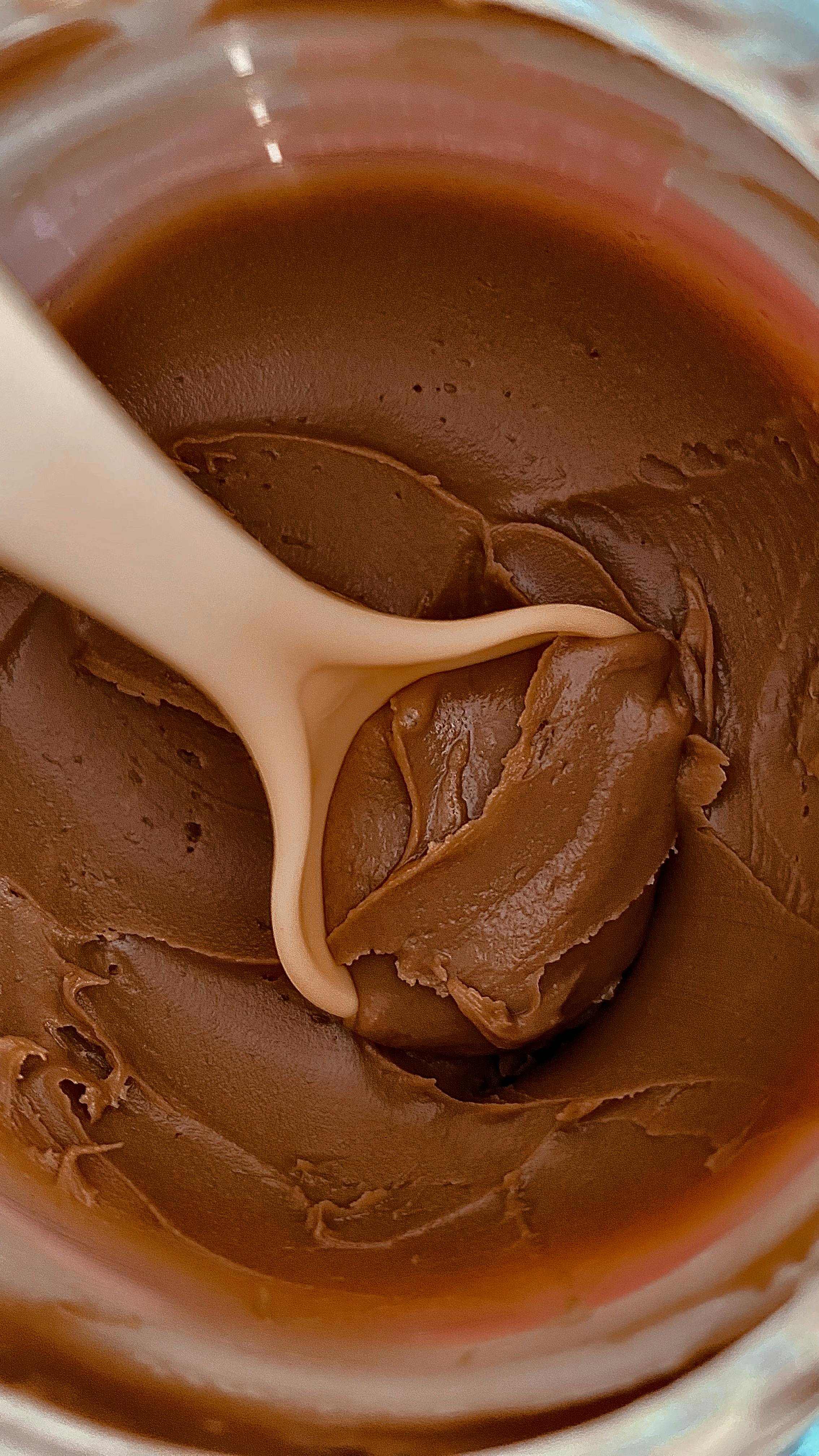 a spoon is scooping out chocolate from a jar