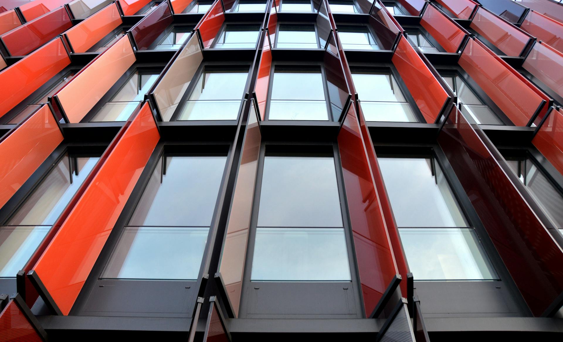 Low angle view of a modern office building with striking red panels and glass windows.