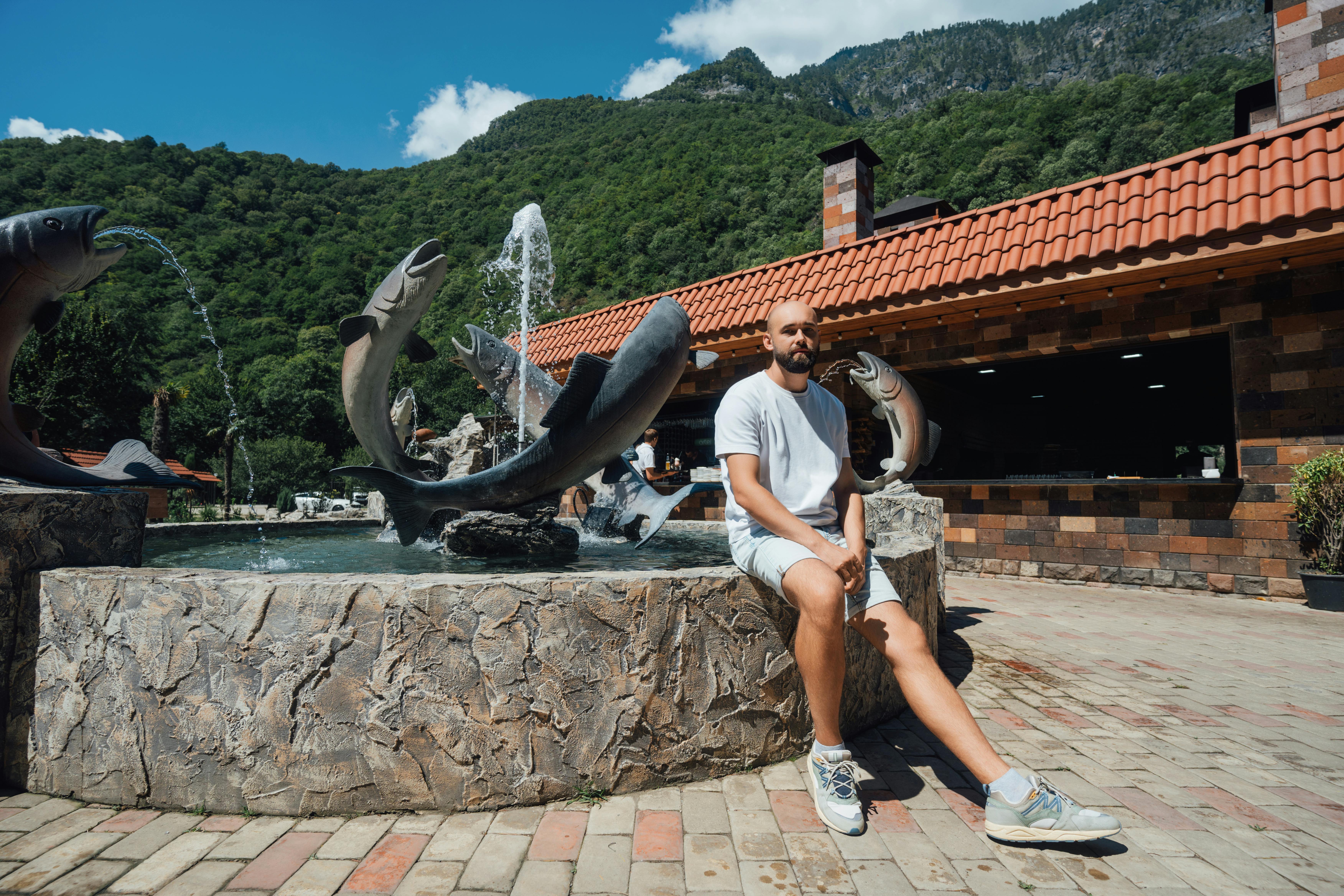 a man sitting on a bench in front of a fountain