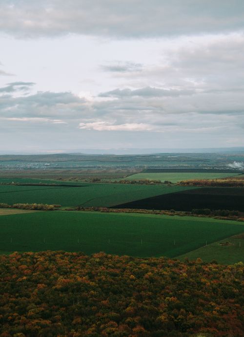 Free Scenic aerial view of lush green fields and distant hills under a cloudy sky in Bashkortostan, Russia. Stock Photo