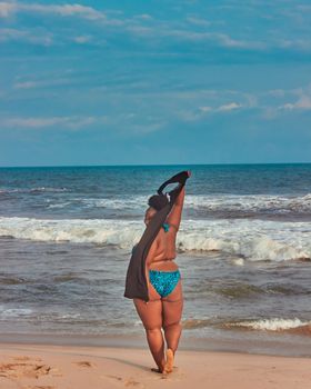 A woman enjoying summer at the beach in a blue bikini, embracing the ocean breeze.