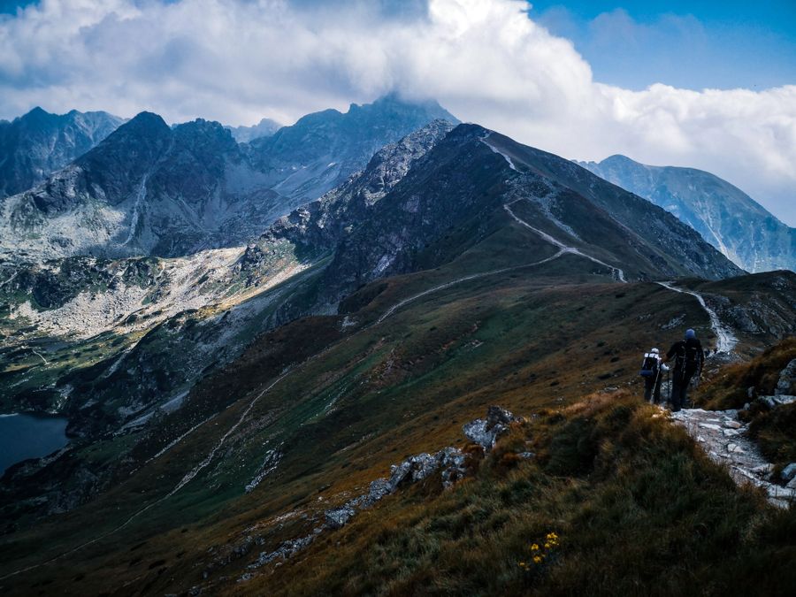 Hikers on a ridge path below a dramatic sky — photo by Monika Balciuniene on Pexels