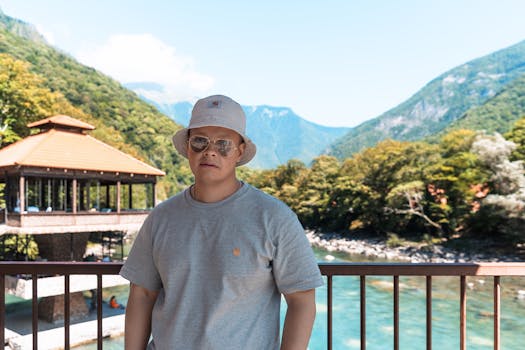 Portrait of a man by a scenic lake in Гагра, surrounded by lush mountains.
