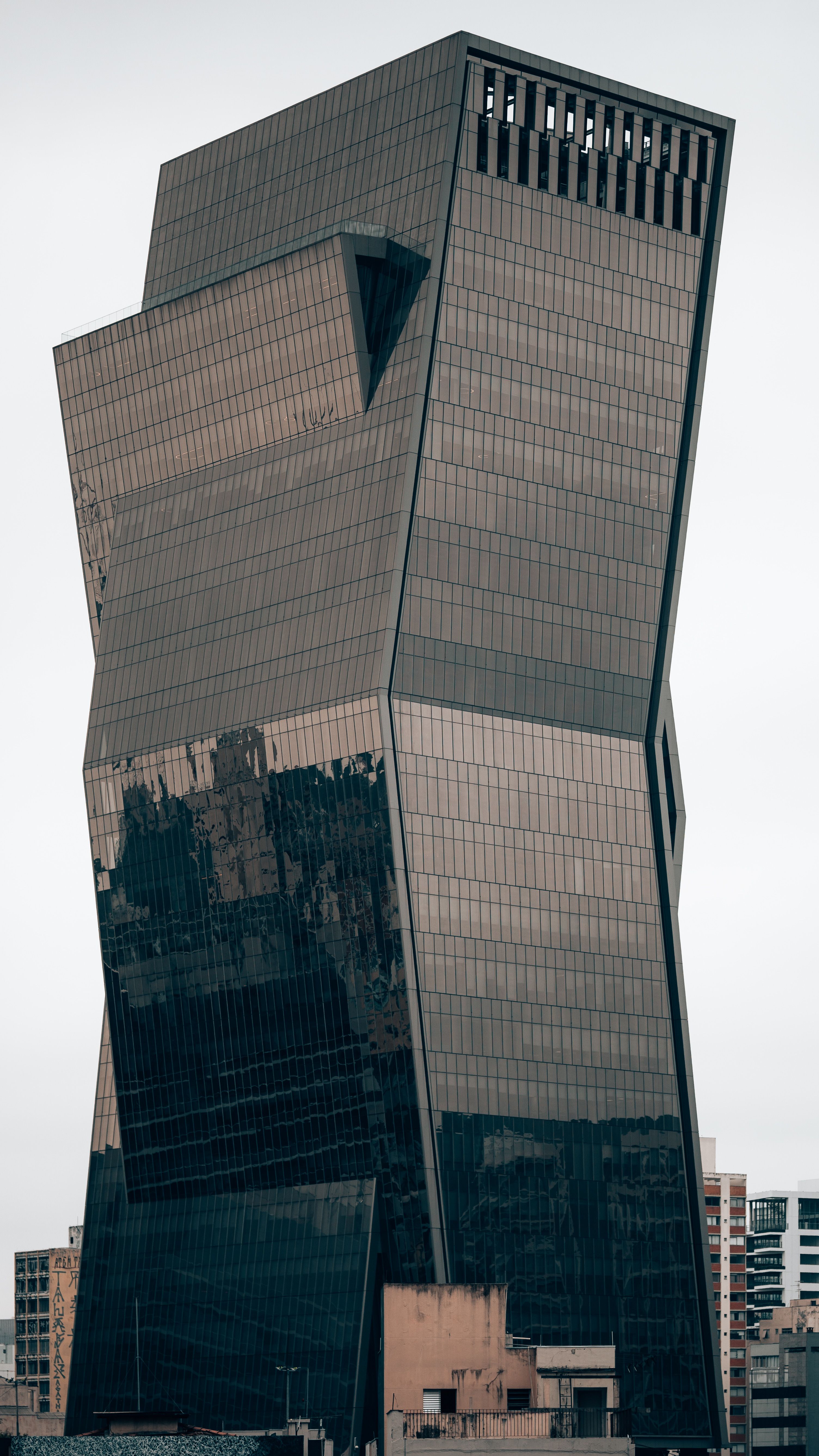 Fotomural Rascacielos de diseño llamativo con vidrio reflectante en un entorno urbano.