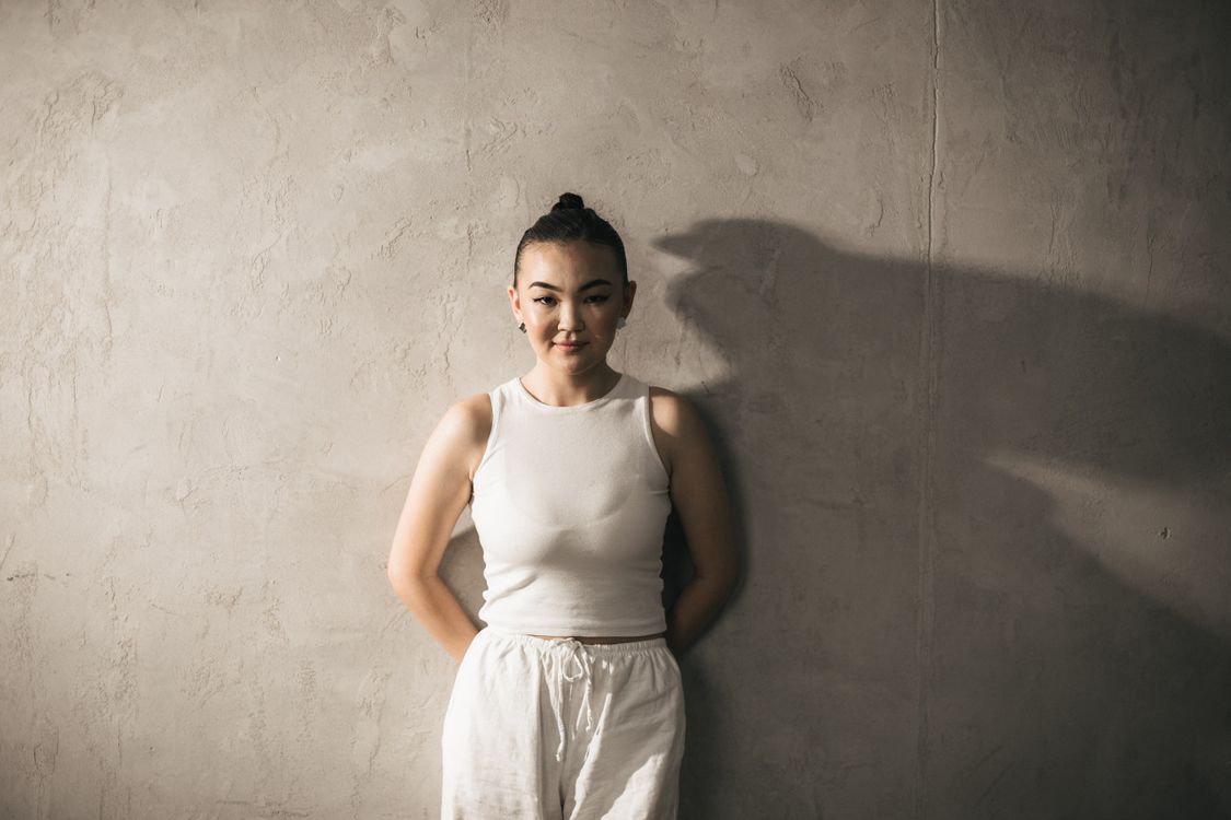 A woman in white top and pants standing against a wall · Free Stock Photo