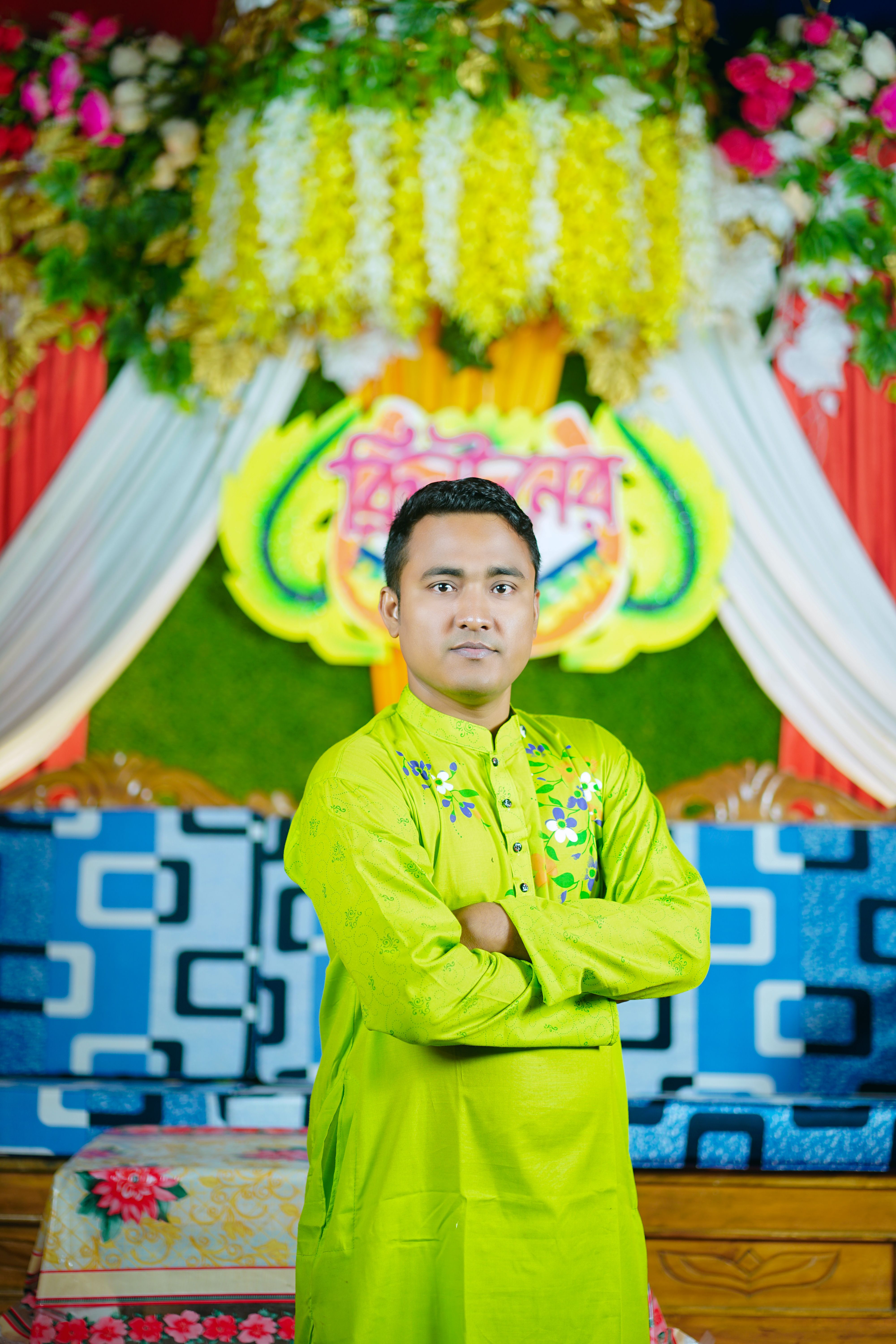 Man in vibrant traditional attire at an indoor Bengali celebration in Bangladesh.