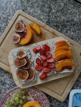 Delicious fruit-topped crispbreads with figs, strawberries, and peaches on a rustic wooden board.
