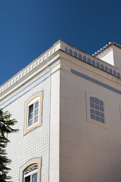 Free A classic white building facade with elegant windows against a clear blue sky. Stock Photo