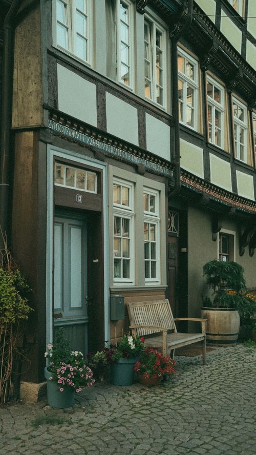Free Quaint European townhouse facade with flowers and cobblestone street in a historic setting. Stock Photo