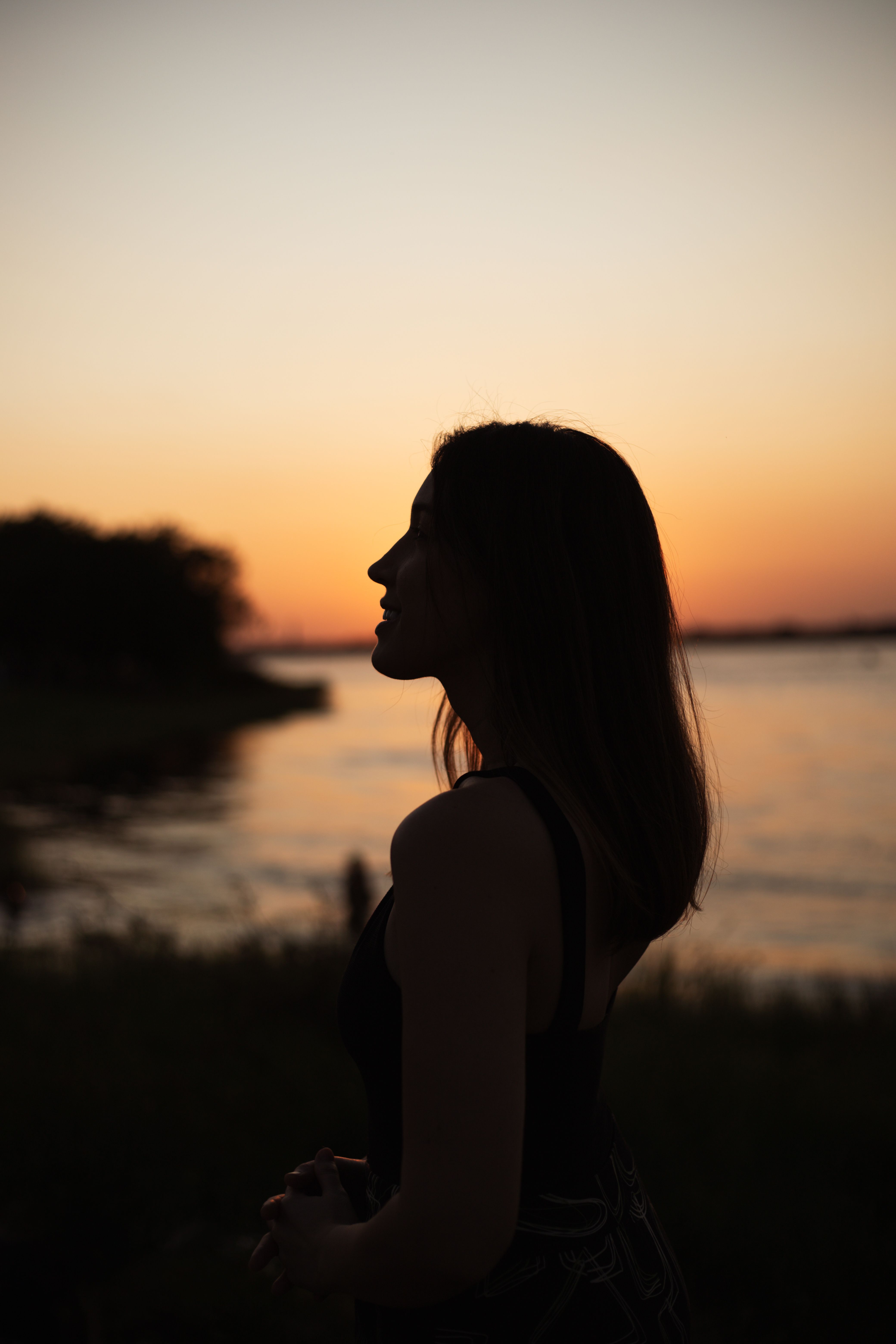 A woman standing by the water at sunset · Free Stock Photo