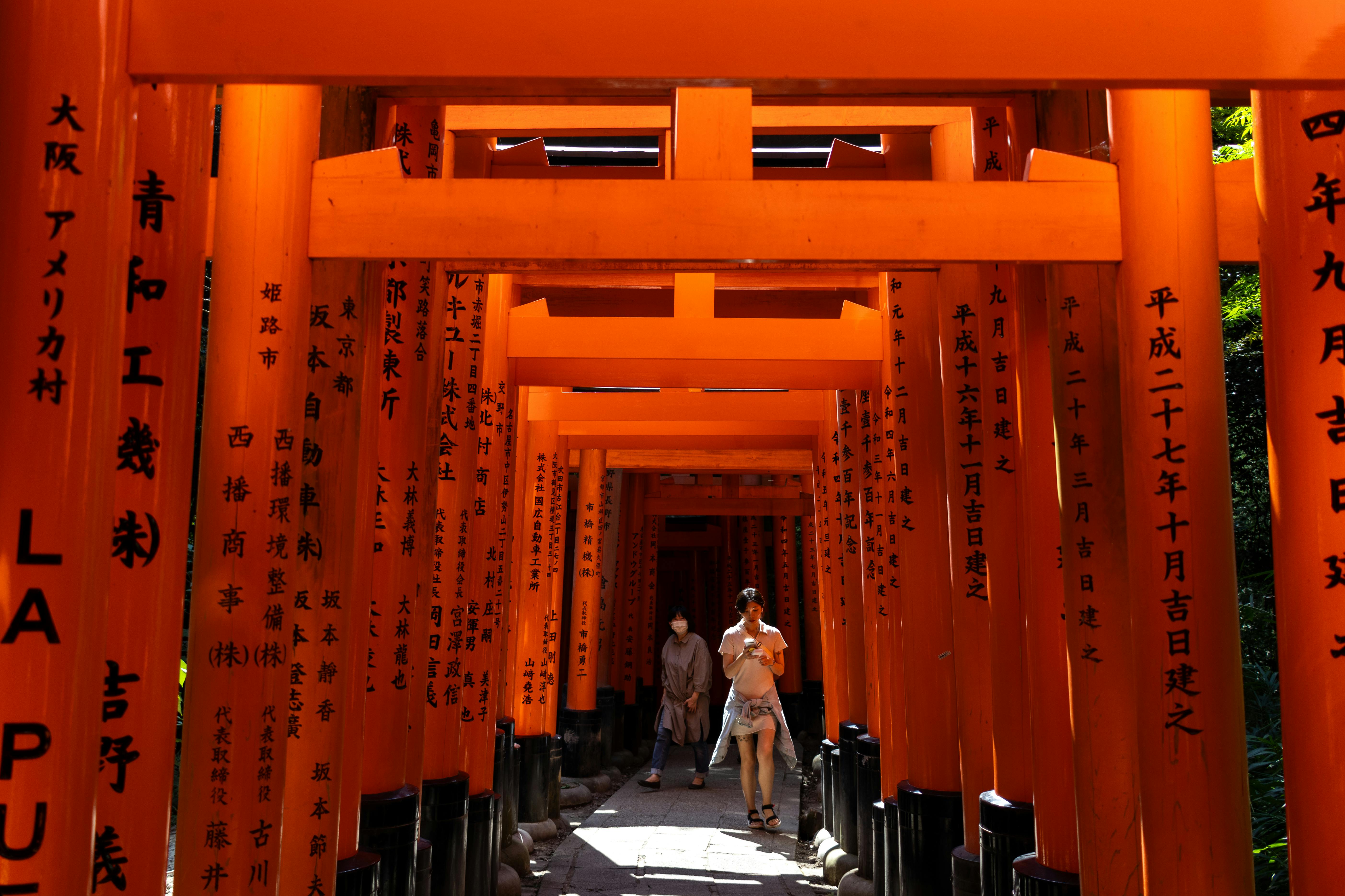 a person walking through a tunnel of orange tori gates