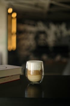Stylish coffee with cream in a glass cup on a wooden table, indoors.