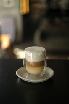Stylish latte macchiato with layered coffee and milk foam in a modern double wall glass.