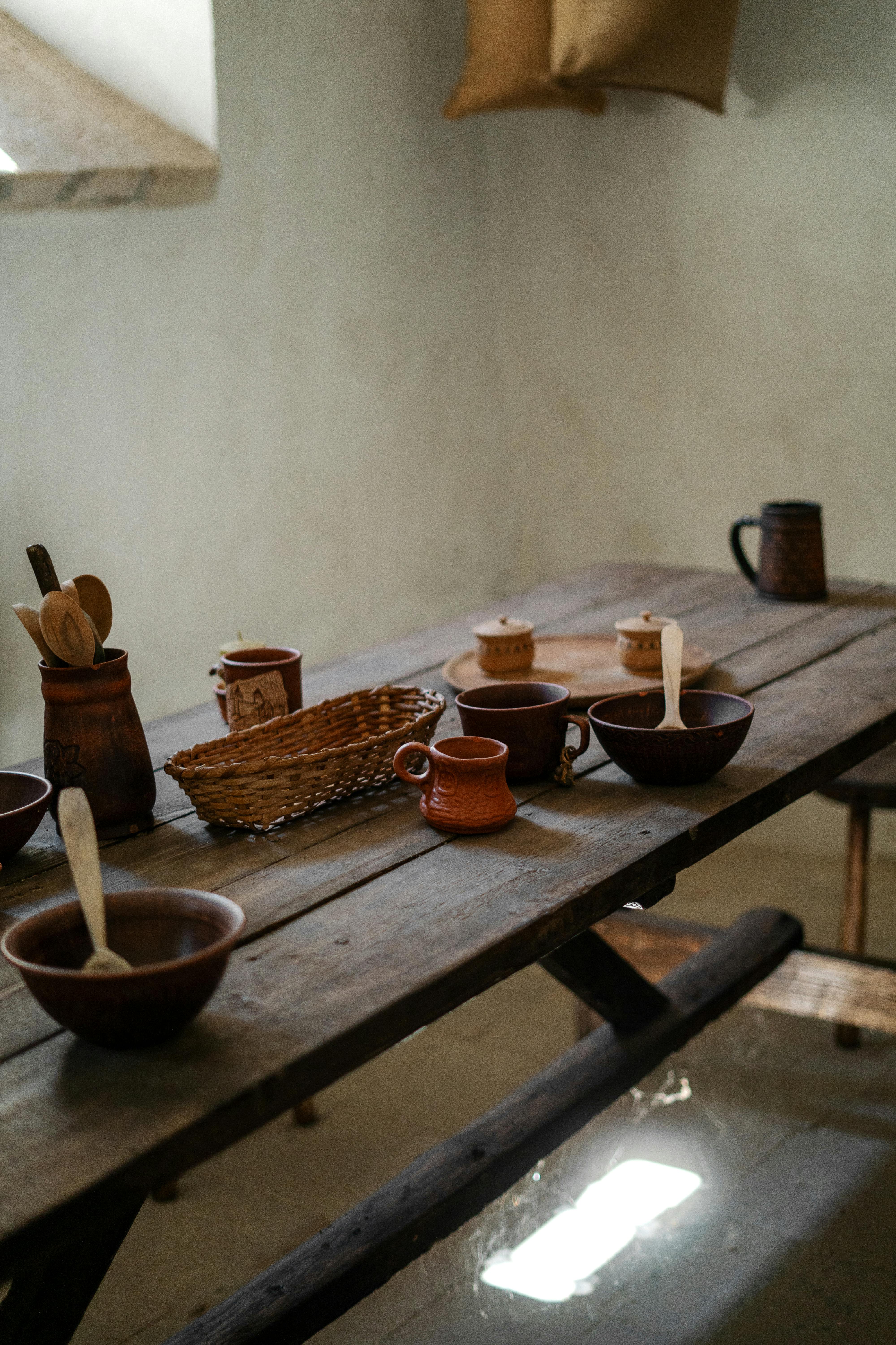 A rustic kitchen table adorned with traditional clay cookware and wooden utensils, creating a cozy ambience.