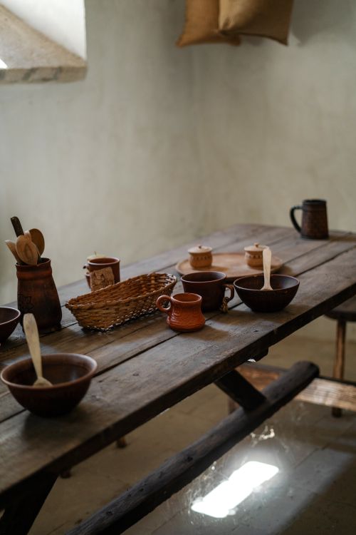 Free A rustic kitchen table adorned with traditional clay cookware and wooden utensils, creating a cozy ambience. Stock Photo