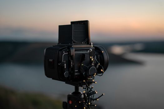 Decorative vintage camera on tripod overlooking scenic sunset landscape in Ukraine.