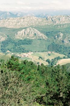 Breathtaking view of rugged terrain in Gijón, Spain, with lush greenery and mountainous backdrop.