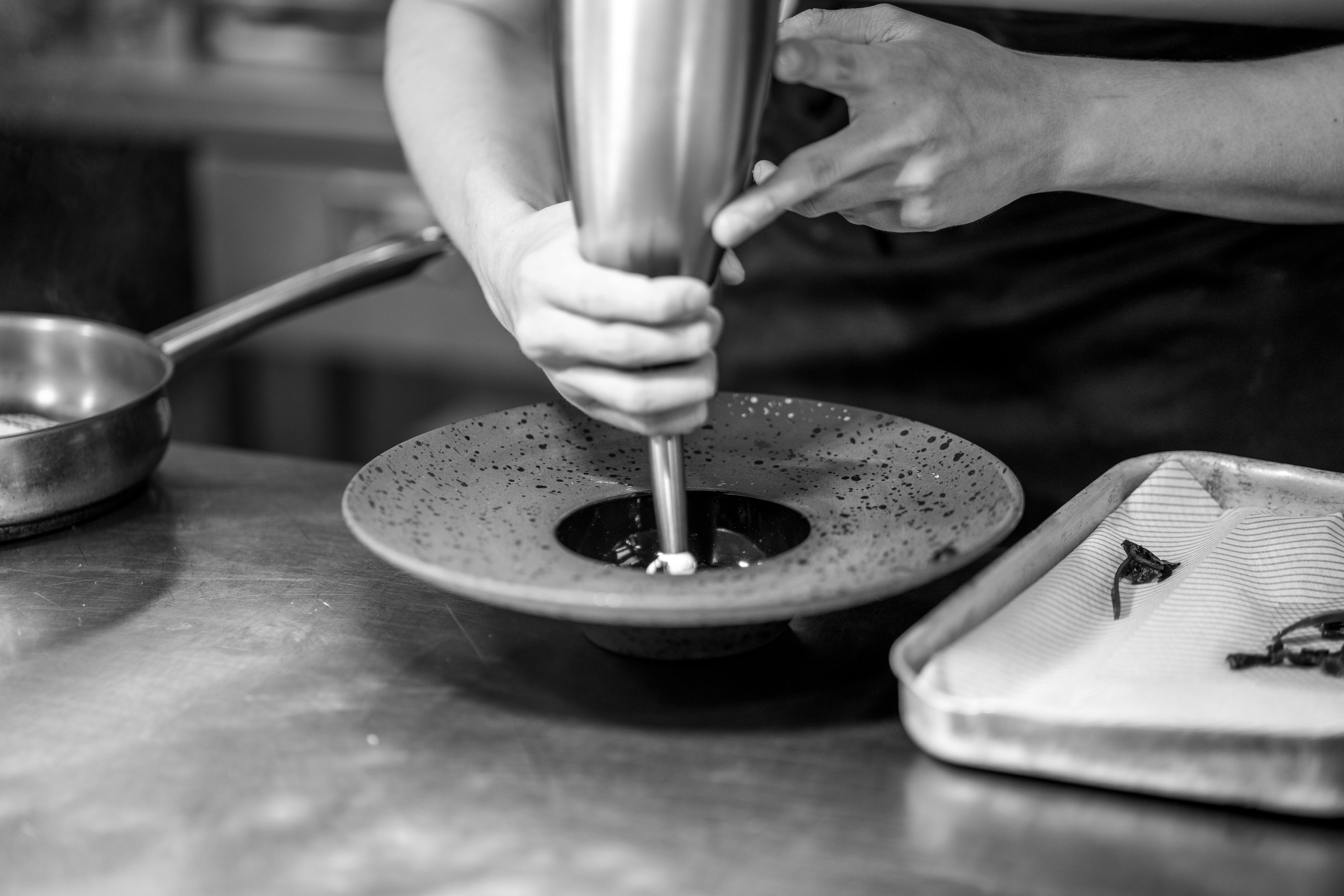 İspanya'da modern bir mutfakta özenle yemek hazırlayan profesyonel bir şef, gastronomi alanındaki kariyer fırsatlarını ve başarıyı simgeliyor.