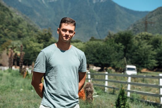 A young man standing outdoors with a scenic mountain view in Gagra. Perfect for travel and lifestyle themes.