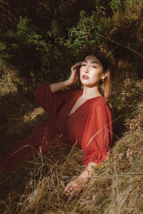 Free A beautiful woman in a red dress enjoys a sunny day outdoors, surrounded by nature. Stock Photo