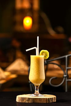 Delicious tropical fruit smoothie with kiwi slice served in a tall glass, perfect for summer refreshment.