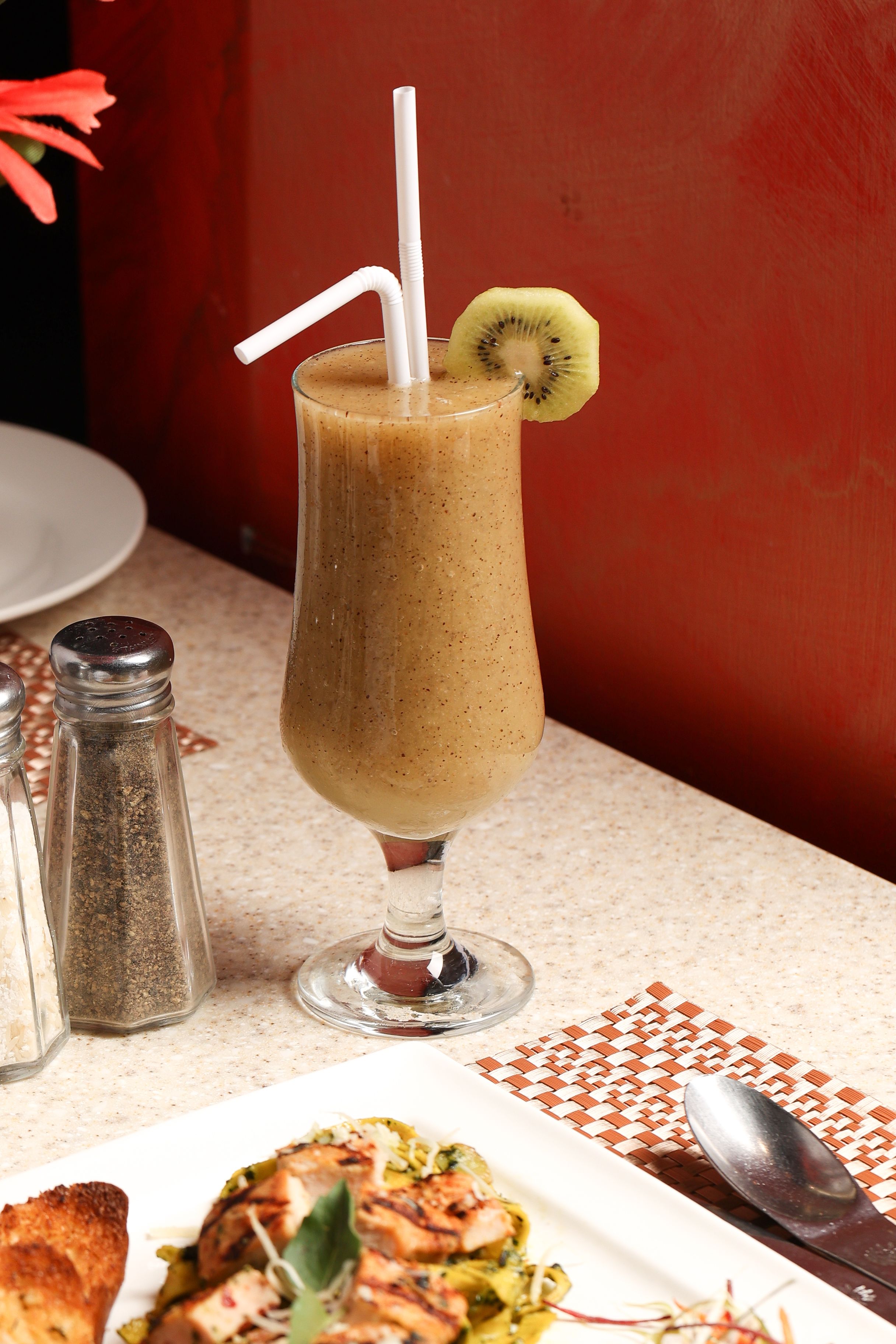 Delicious kiwi smoothie served in a tall glass with dinner setting.
