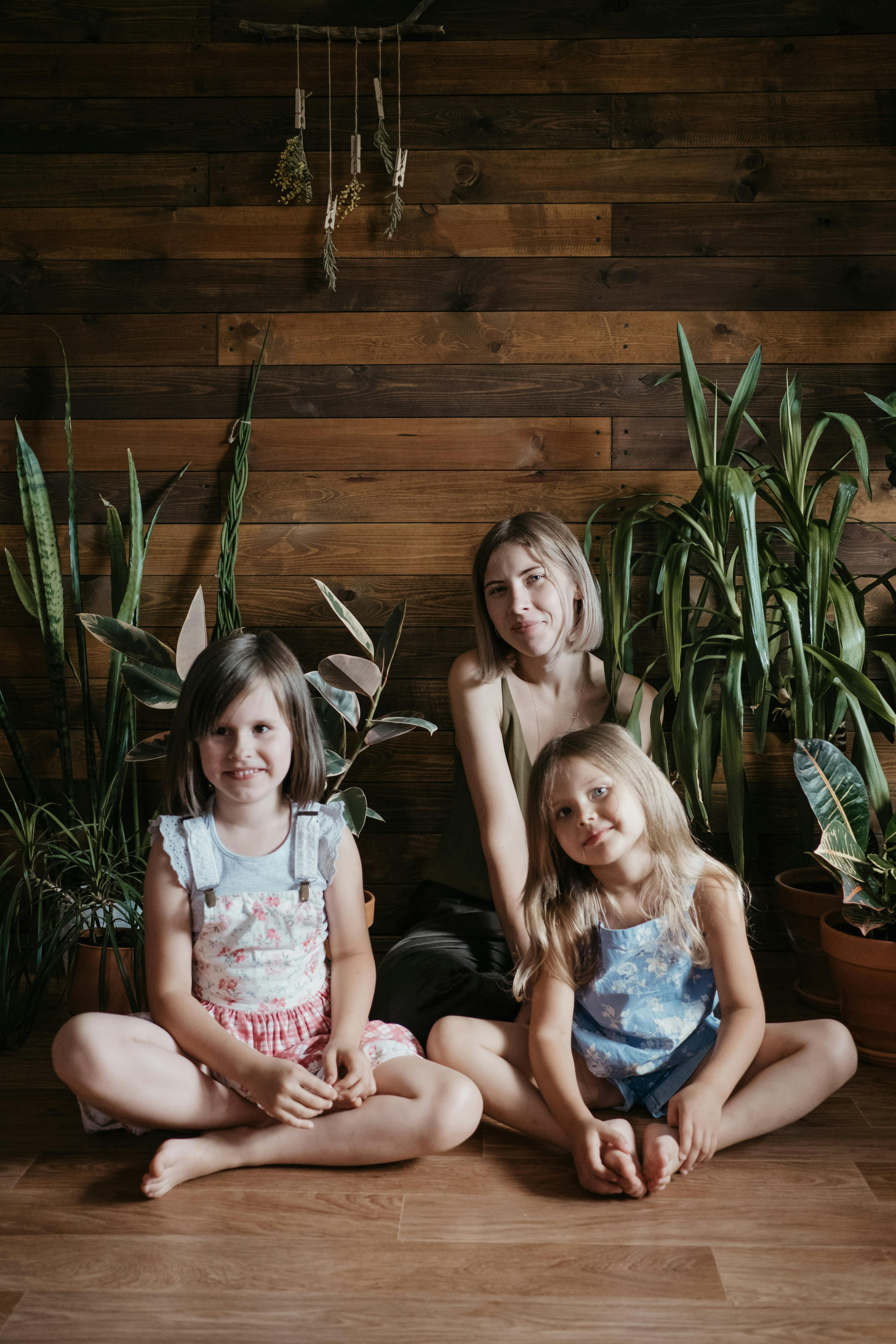 Three Girls Sitting Beside Green Indoor Plants