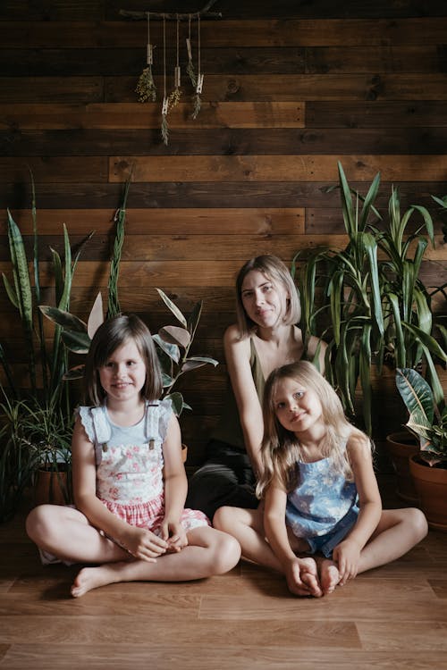 Three Girls Sitting Beside Green Indoor Plants