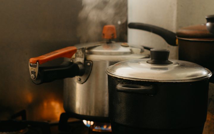 Steaming pots on a kitchen stove with smoke rising in a cozy indoor setting.