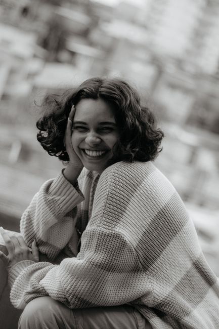 A cheerful woman in a striped sweater enjoying a moment outdoors, radiating warmth and happiness.