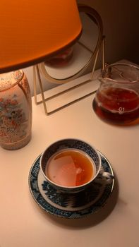 Elegant still life of tea in a patterned cup with warm lighting, perfect for a peaceful morning.