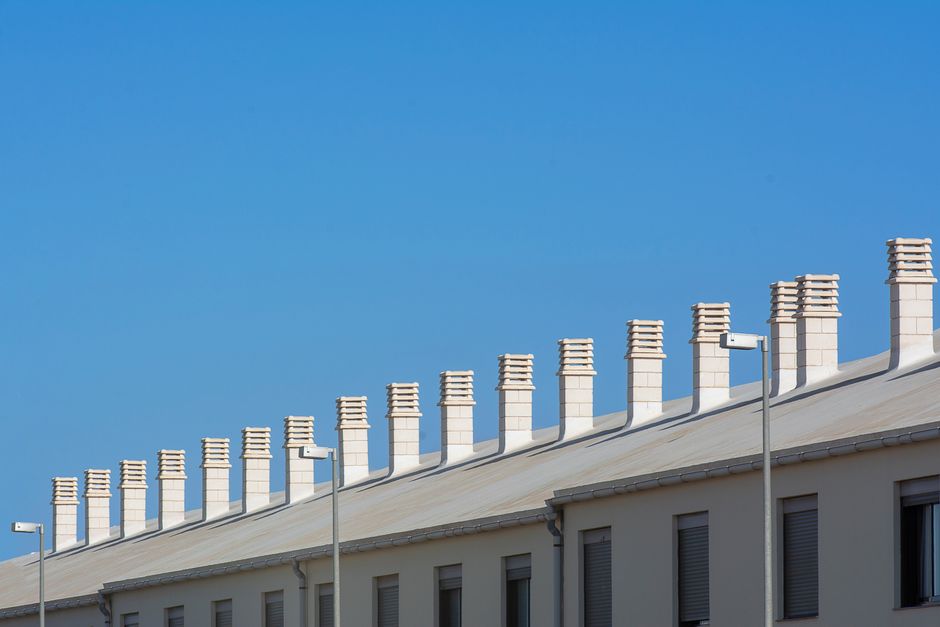 Una fila de chimeneas modernas y blancas en el tejado bajo un cielo azul brillante en Arrecife, España.