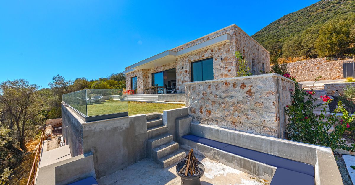 Modern stone villa with glass accents in a sunny and scenic summer setting, ideal for travel and relaxation.