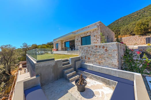Modern stone villa with glass accents in a sunny and scenic summer setting, ideal for travel and relaxation.