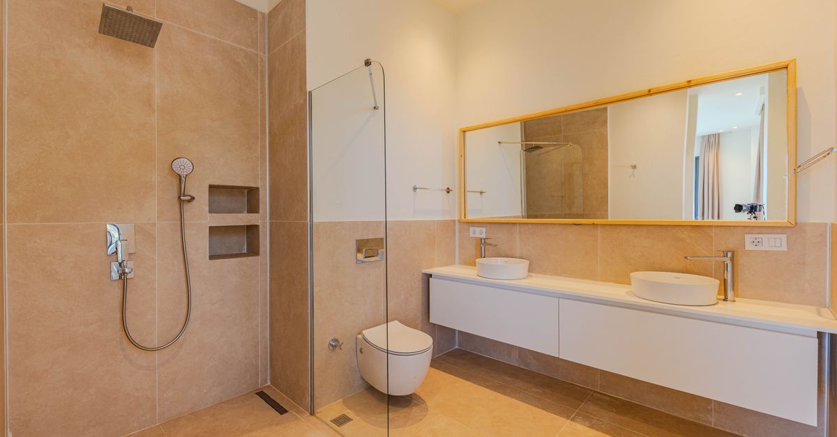 Elegant minimalist bathroom featuring beige tiles, large mirror, and double sinks.