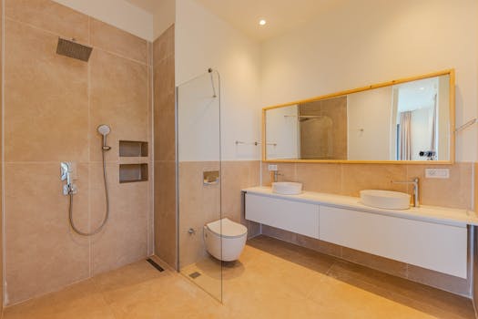 Elegant minimalist bathroom featuring beige tiles, large mirror, and double sinks.