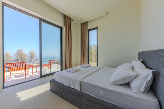 Bright minimalist bedroom featuring a bed, large windows, and ocean view.