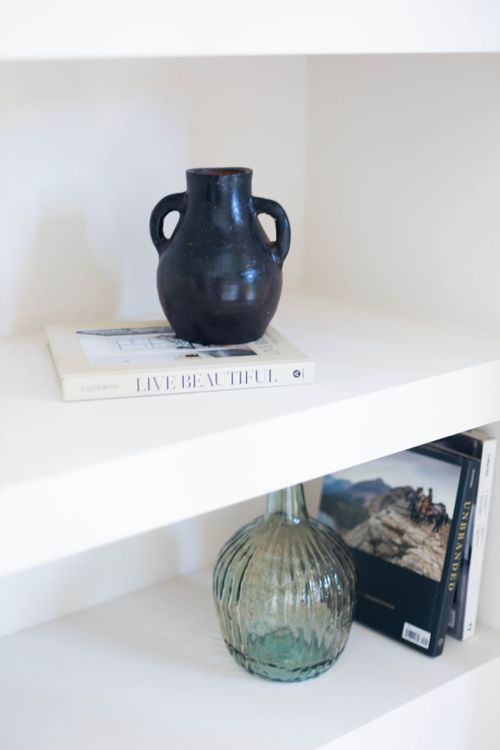 Free A minimalist shelf featuring a ceramic vase and books, exuding elegance and simplicity. Stock Photo