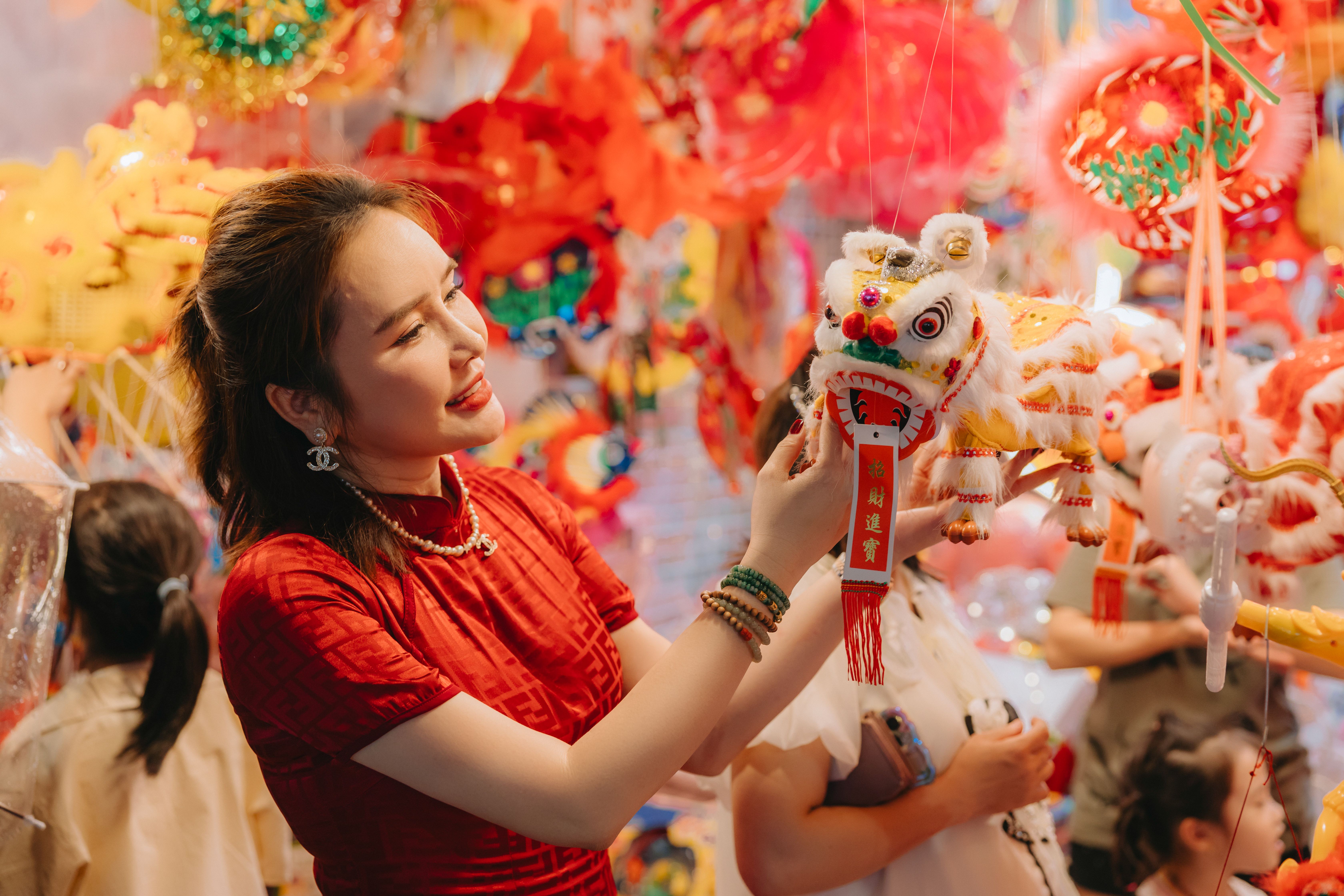 Wanita tersenyum di depan dekorasi festival berwarna-warni merayakan Tahun Baru Imlek. Via Pexels (by HONG SON)