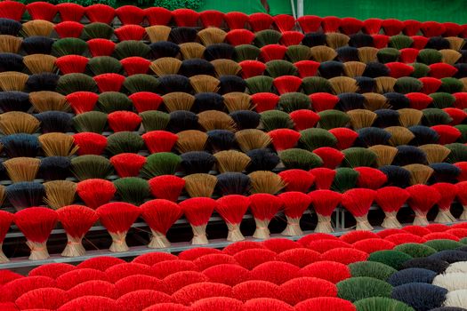 Vibrant broomsticks arranged patternfully in outdoor display showcasing rich colors.