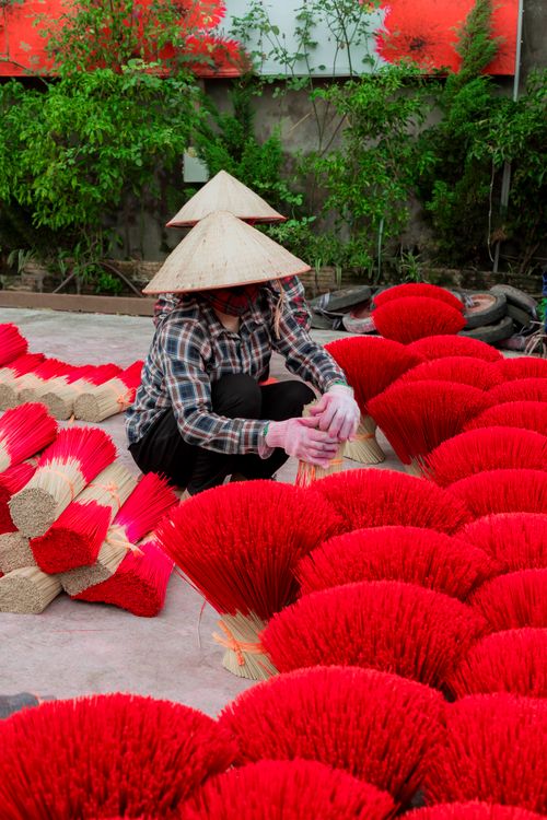 Free Traditional incense sticks being prepared outdoors by an adult wearing a conical hat. Stock Photo