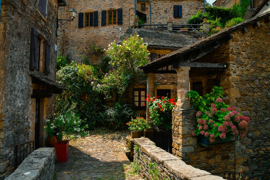 Picturesque stone buildings with lush flowers in a tranquil village setting.