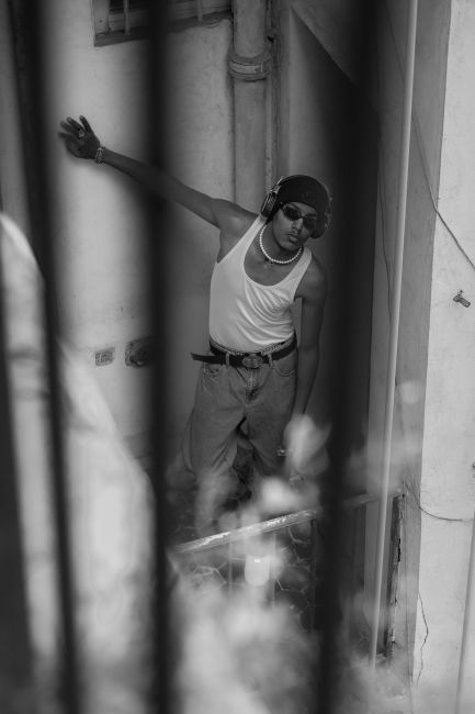 Black and white portrait of a young man in urban setting with headphones and sunglasses.