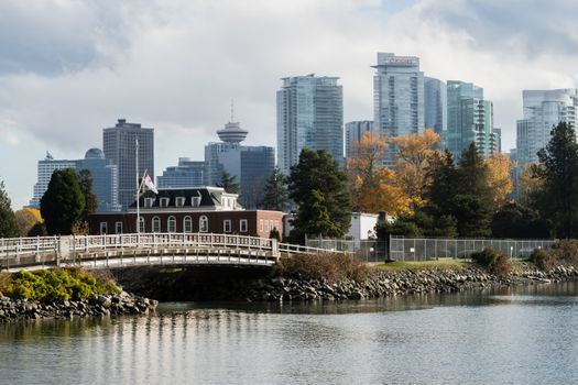 Explore a picturesque fall view of Vancouver's downtown skyline with a tranquil waterfront and vibrant trees.